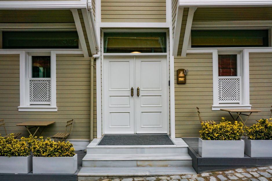 Charming entrance of a house featuring white double doors and outdoor seating.