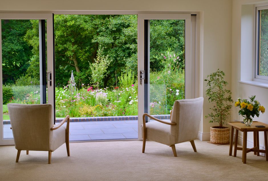 Cozy interior with armchairs and greenery view through large sliding glass doors.