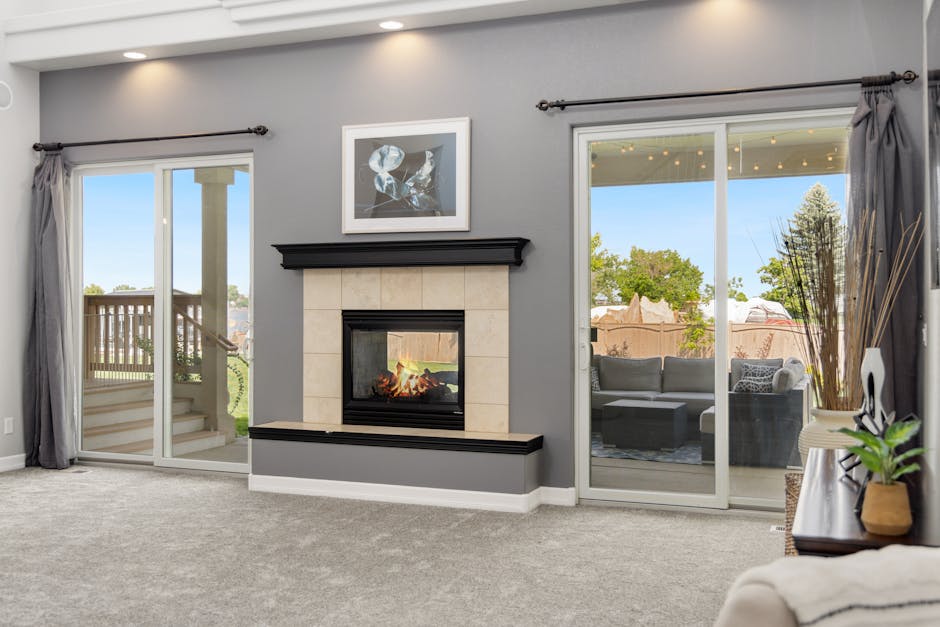 Elegant living room interior with a fireplace, gray walls, and sliding doors leading to a patio.