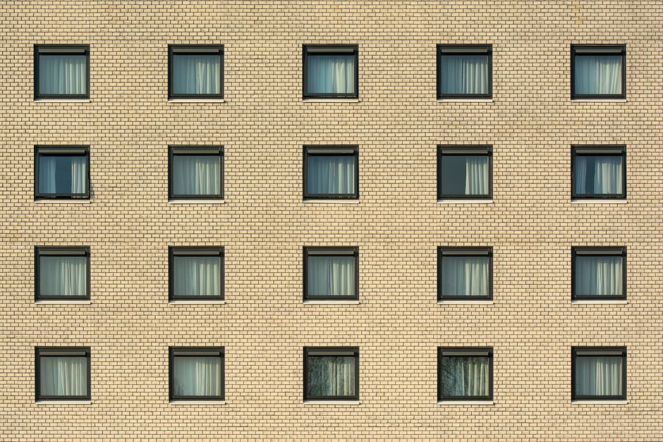 Front view of a yellow brick building with evenly spaced windows, showcasing architectural symmetry.